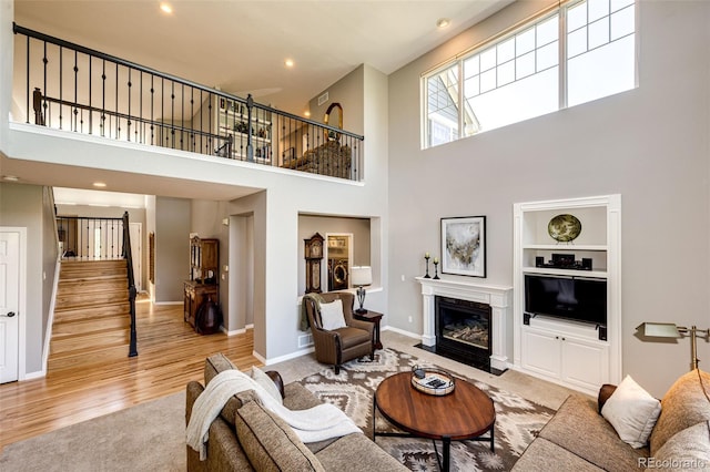 22685 E Calhoun Pl, Aurora, CO 80016 - living area featuring stairs, a towering ceiling, wood finished floors, a fireplace with flush hearth, and built in features
