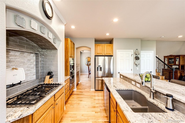 22685 E Calhoun Pl, Aurora, CO 80016 - kitchen featuring stainless steel appliances, a sink, light wood finished floors, decorative backsplash, and light stone countertops