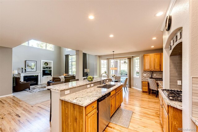 22685 E Calhoun Pl, Aurora, CO 80016 - kitchen with a sink, a fireplace, appliances with stainless steel finishes, light wood-style flooring, and an island with sink