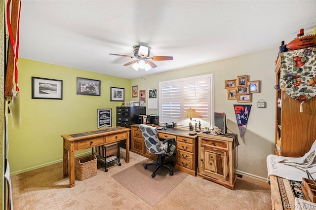carpeted office space with ceiling fan and baseboards