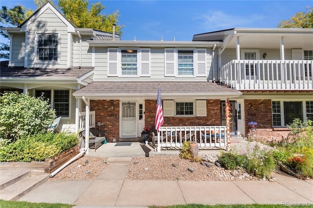 townhome / multi-family property featuring a porch, brick siding, a shingled roof, and a balcony