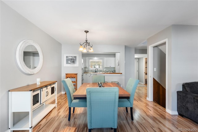 dining room featuring light wood finished floors, baseboards, and a chandelier