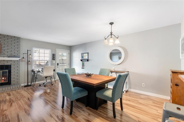 dining room with a brick fireplace, baseboards, and wood finished floors