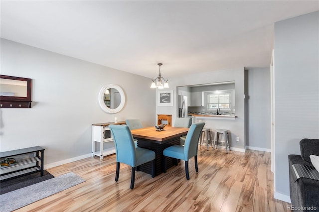 dining space with a chandelier, baseboards, and light wood finished floors