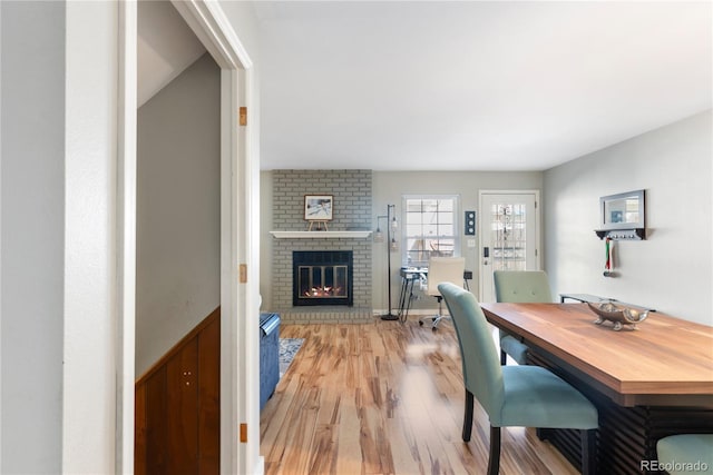 dining room with light wood-type flooring and a brick fireplace