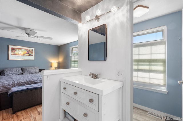 interior space with baseboards, visible vents, ceiling fan, light wood-style floors, and a sink