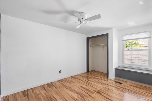 unfurnished bedroom featuring baseboards, visible vents, a ceiling fan, light wood-style floors, and a closet