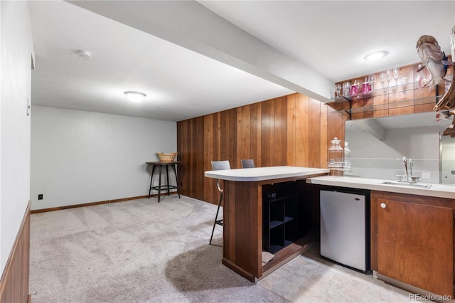 bar with baseboards, light colored carpet, indoor wet bar, fridge, and a sink