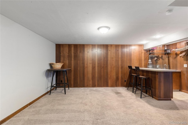 bar with baseboards, wood walls, light colored carpet, and wet bar