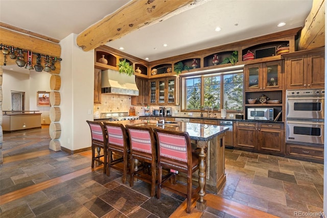 kitchen with premium range hood, tasteful backsplash, a kitchen island, a kitchen bar, and stainless steel appliances