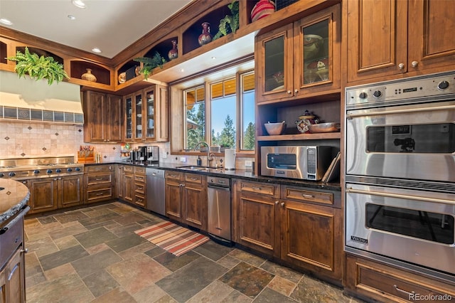 kitchen with stainless steel appliances, tasteful backsplash, sink, and dark stone counters