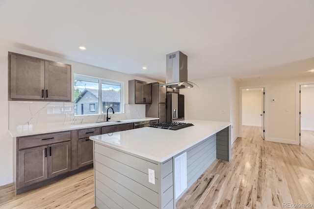 kitchen with island range hood, tasteful backsplash, light hardwood / wood-style flooring, and a center island