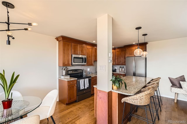 kitchen featuring pendant lighting, stainless steel appliances, a breakfast bar, and hardwood / wood-style floors