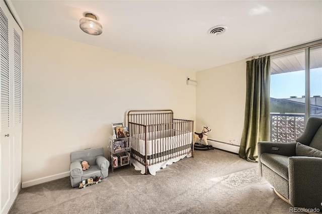 carpeted bedroom featuring a crib and a baseboard radiator