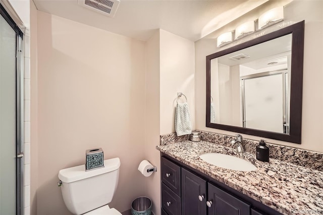 bathroom featuring vanity, an enclosed shower, and toilet