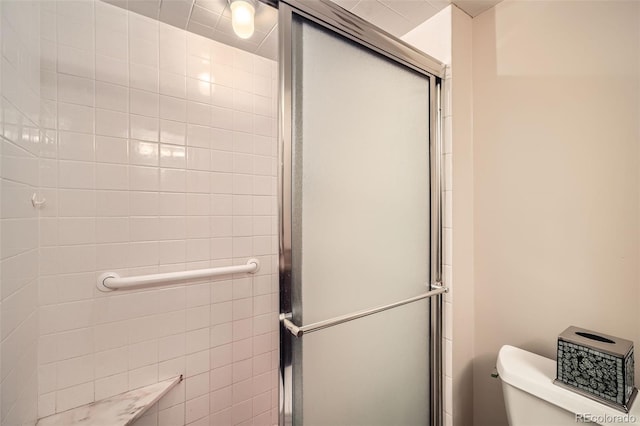 bathroom featuring toilet and a shower with shower door