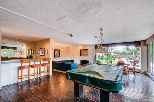 game room featuring bar, pool table, and a textured ceiling