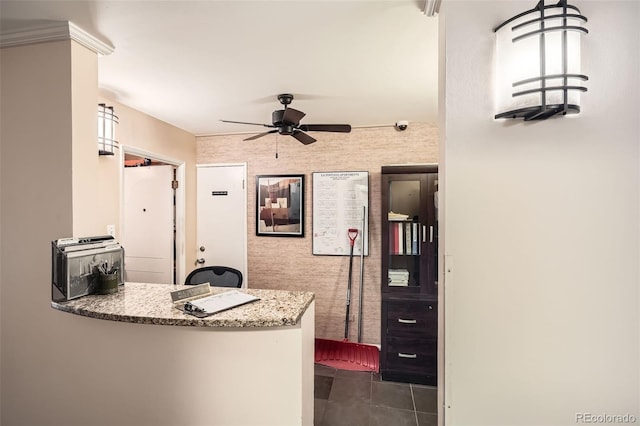 kitchen featuring dark tile patterned flooring, light stone countertops, kitchen peninsula, and ceiling fan