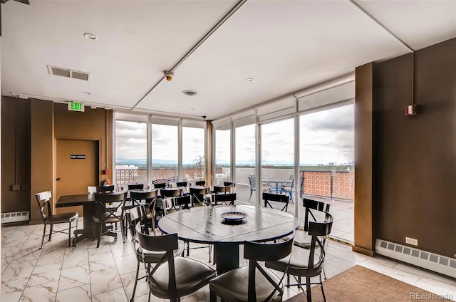 dining area featuring expansive windows, a water view, and baseboard heating