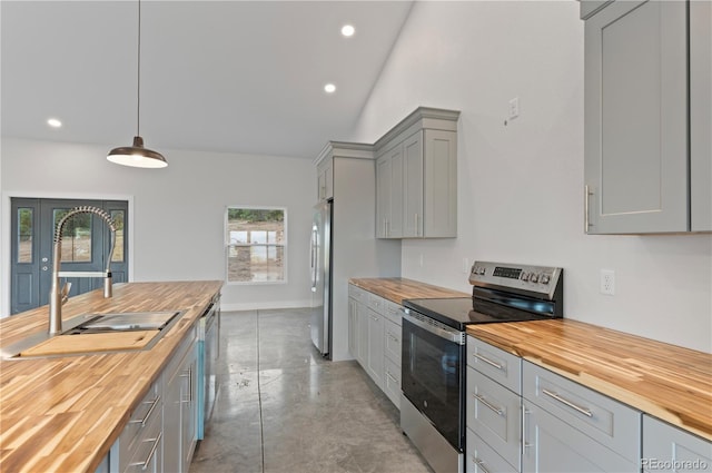 kitchen with gray cabinetry, sink, stainless steel appliances, pendant lighting, and wooden counters