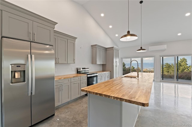 kitchen with wooden counters, a wall mounted AC, hanging light fixtures, gray cabinetry, and stainless steel appliances