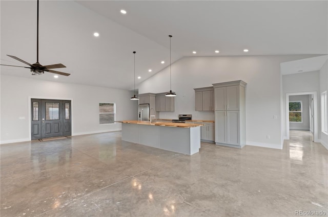 kitchen with gray cabinetry, appliances with stainless steel finishes, butcher block counters, a large island, and high vaulted ceiling