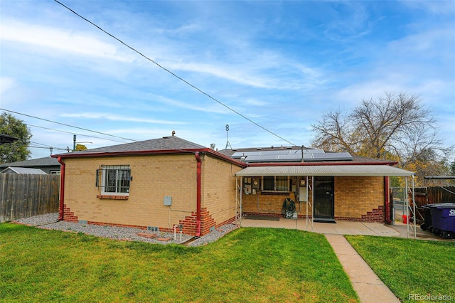 rear view of property with a patio, solar panels, and a lawn