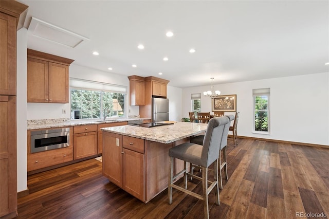 16 Scott Dr N, Broomfield, CO 80020 - kitchen with dark wood finished floors, a kitchen island, light stone counters, recessed lighting, and a breakfast bar