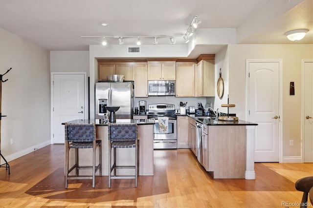 620 11th St Unit 206, Golden, CO 80401 - kitchen with appliances with stainless steel finishes, a breakfast bar, dark countertops, light wood-type flooring, and a kitchen island