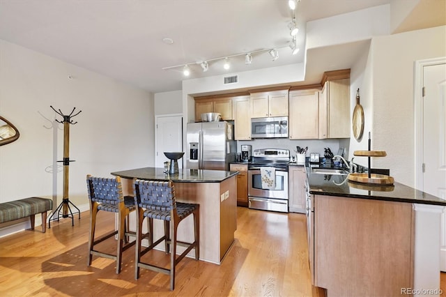 620 11th St Unit 206, Golden, CO 80401 - kitchen with stainless steel appliances, a kitchen bar, a kitchen island, light wood-style flooring, and dark stone counters