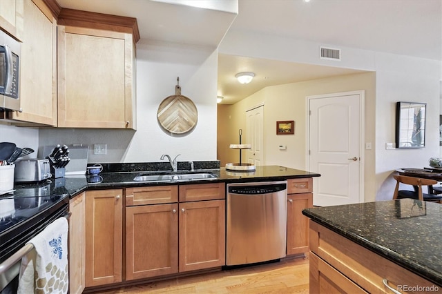 620 11th St Unit 206, Golden, CO 80401 - kitchen with stainless steel appliances, dark stone countertops, light wood-style floors, brown cabinetry, and a peninsula