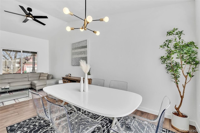 dining area featuring hardwood / wood-style flooring, vaulted ceiling, and ceiling fan with notable chandelier