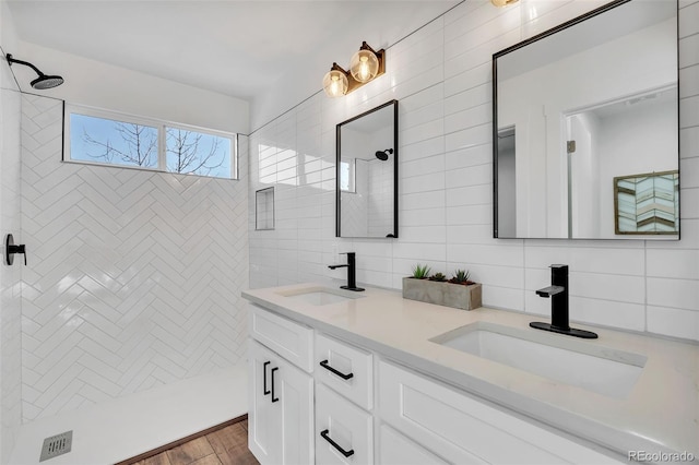 bathroom with tile walls, backsplash, tiled shower, vanity, and wood-type flooring