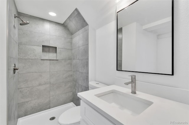 bathroom with vanity, toilet, and a tile shower