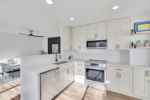 kitchen with sink, white cabinetry, stainless steel appliances, tasteful backsplash, and kitchen peninsula