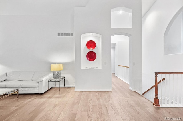 living room featuring a towering ceiling and light hardwood / wood-style floors