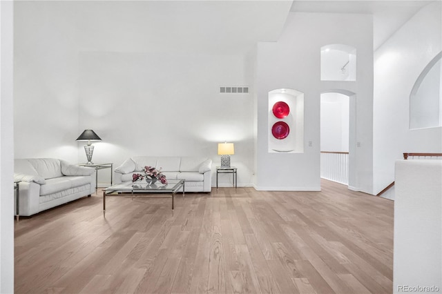 living room with a towering ceiling and light hardwood / wood-style floors