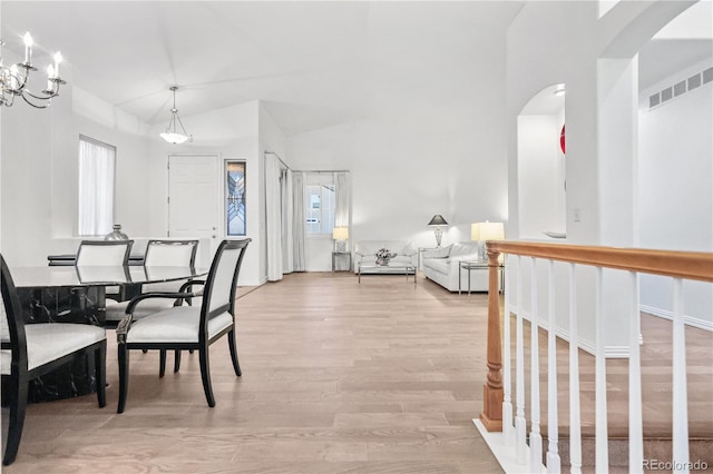 dining space with a chandelier, light hardwood / wood-style floors, and vaulted ceiling