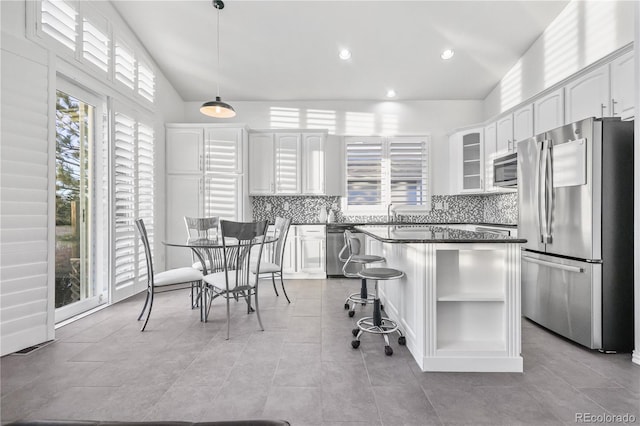 kitchen featuring white cabinets, appliances with stainless steel finishes, a kitchen island, and lofted ceiling