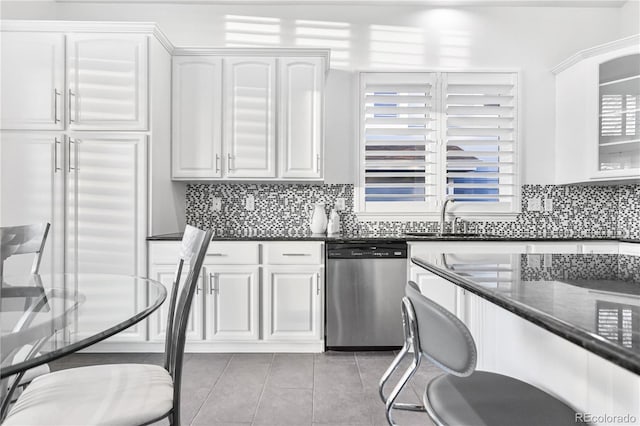 kitchen featuring stainless steel dishwasher, white cabinets, light tile patterned floors, and sink