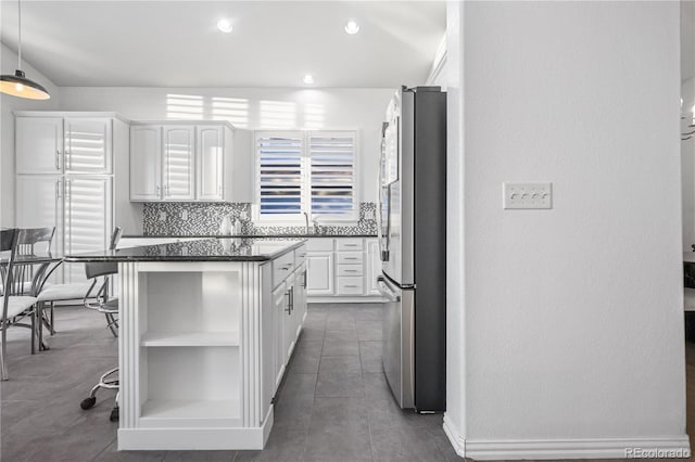 kitchen with white cabinets, decorative backsplash, stainless steel refrigerator, and a kitchen island