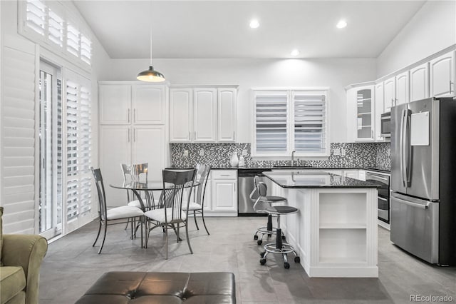 kitchen with appliances with stainless steel finishes, vaulted ceiling, sink, decorative light fixtures, and white cabinets