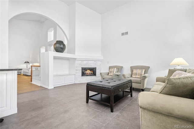 living room featuring a tile fireplace, hardwood / wood-style floors, and a towering ceiling