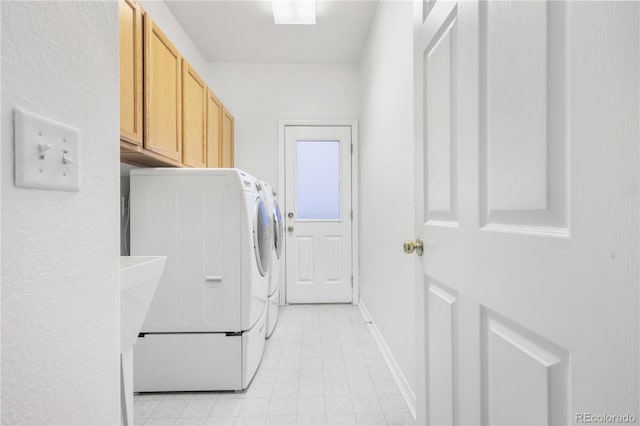 clothes washing area featuring washer and clothes dryer and cabinets