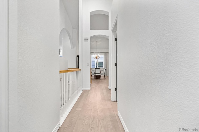 hallway featuring light hardwood / wood-style floors and an inviting chandelier