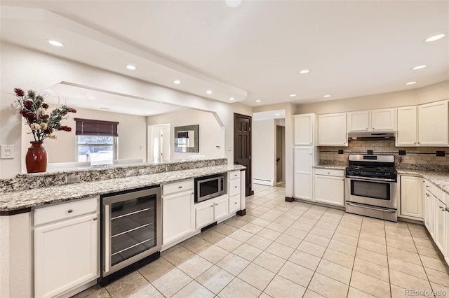 kitchen with light tile patterned floors, appliances with stainless steel finishes, backsplash, beverage cooler, and light stone counters