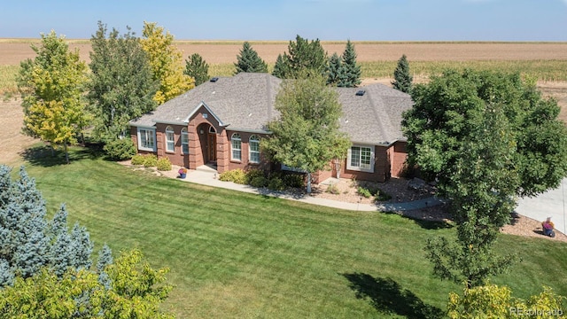 view of front of home with brick siding, a front lawn, and a rural view