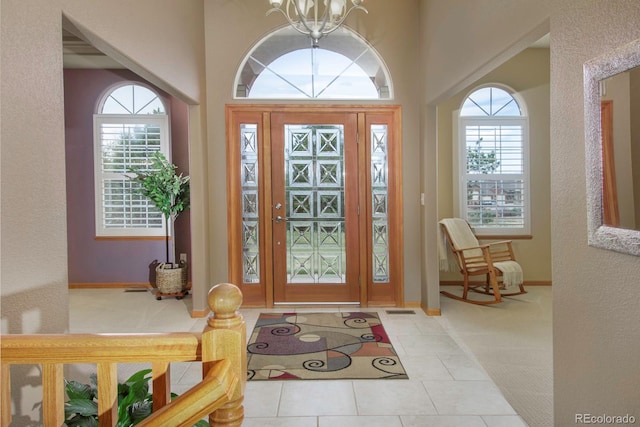 foyer featuring tile patterned floors, carpet flooring, baseboards, and a healthy amount of sunlight