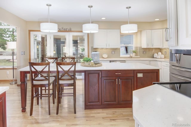 kitchen featuring tasteful backsplash, a center island, a sink, light countertops, and light wood-style flooring