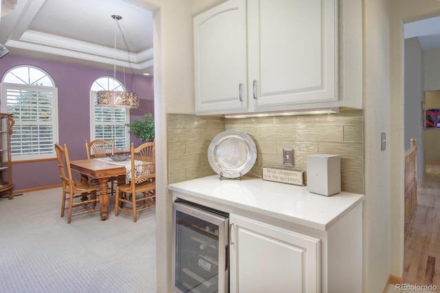 bar with tasteful backsplash, baseboards, crown molding, a tray ceiling, and beverage cooler